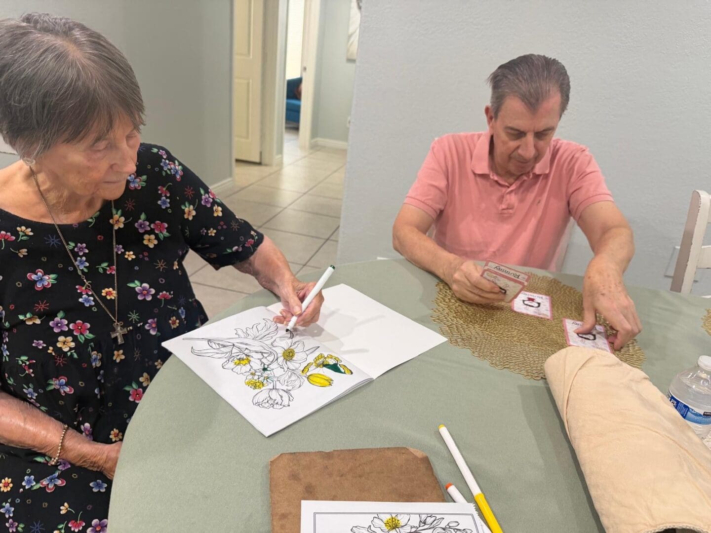 Residents at New Visions Assisted Living in Scottsdale enjoy coloring and card games during engaging indoor summer activities that promote social connection and healthy aging.