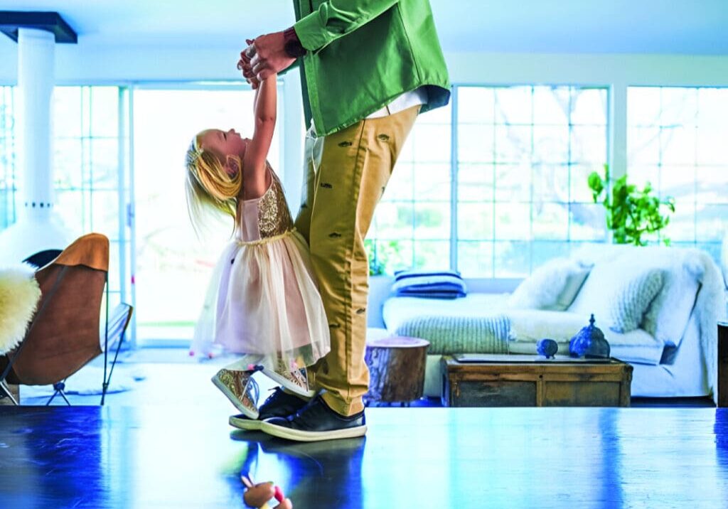 A man and child are dancing on the floor.