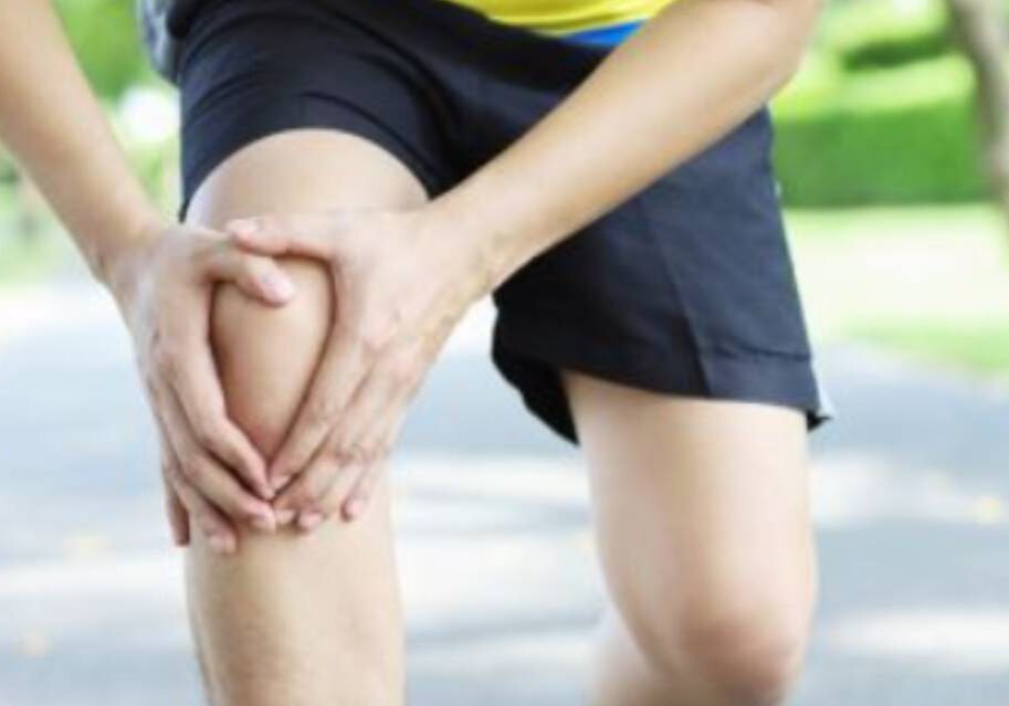 A person with knee pain is holding their hands on the ground.