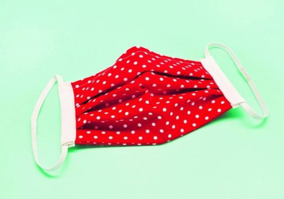 A red and white polka dot face mask on top of a green background.