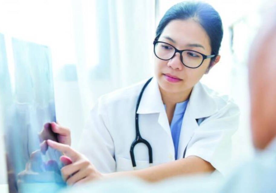 A woman in white lab coat holding a tablet.