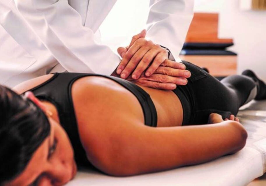 A person is getting their back examined by an osteopath.
