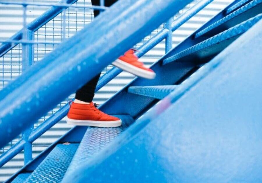 A person with orange shoes is going down some stairs