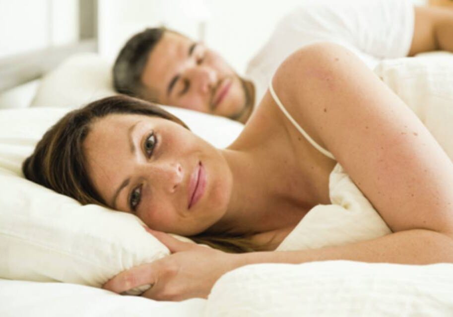 A woman laying in bed next to a man.