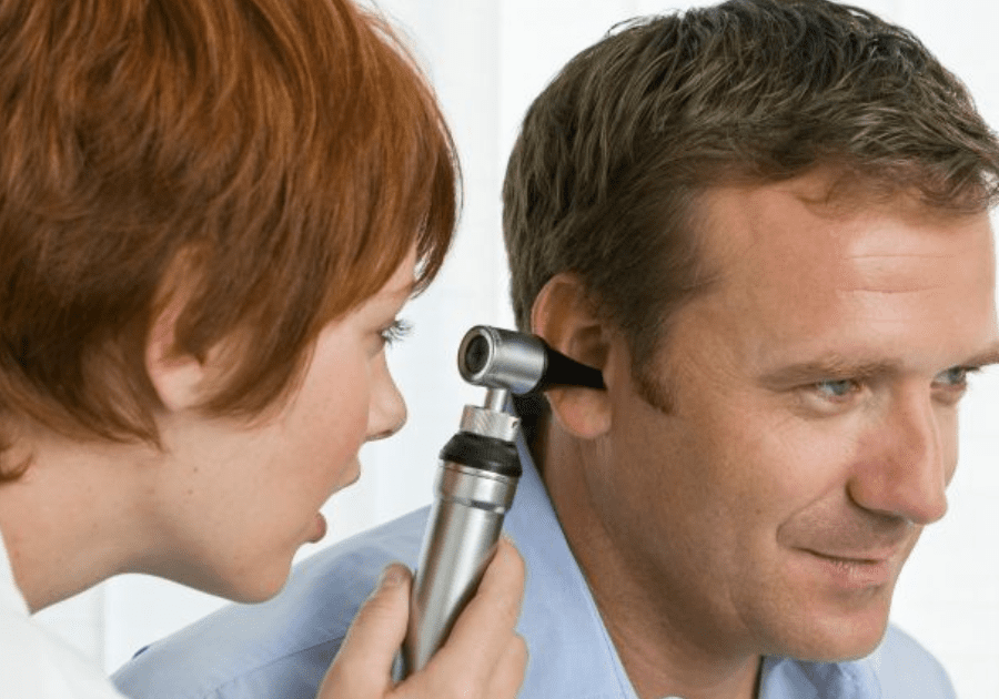 A woman is checking the ear of a man.