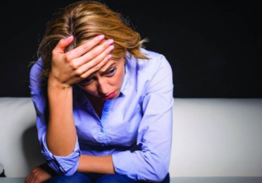 A woman sitting on the ground with her head in her hands.
