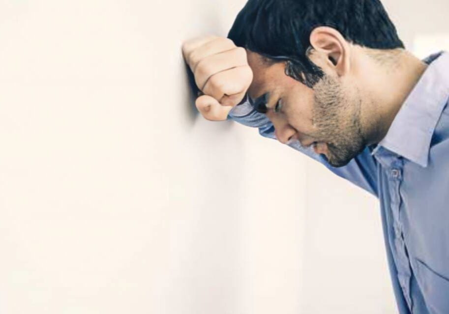 A man leaning against the wall with his head on his hand.