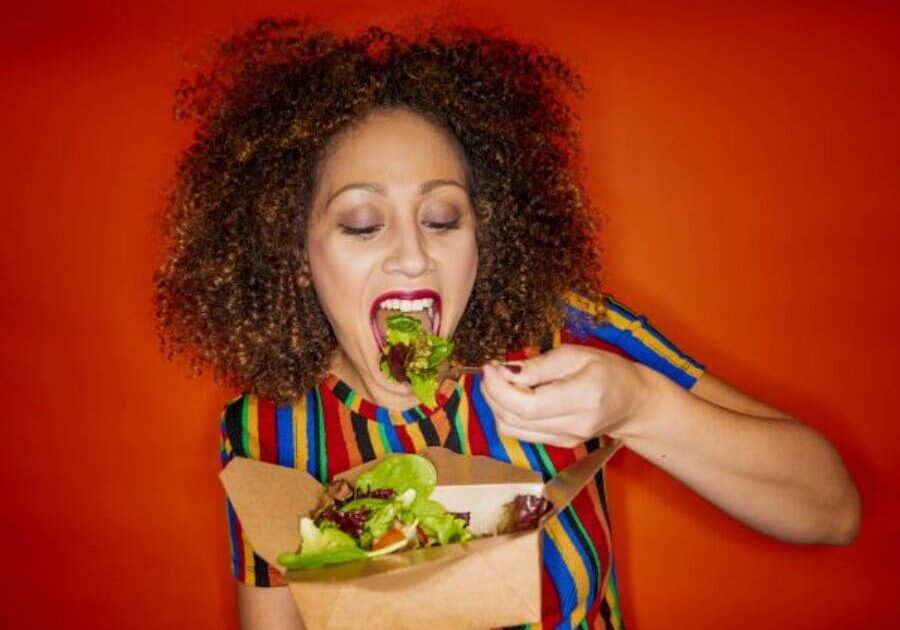 A woman eating food from a paper bag.