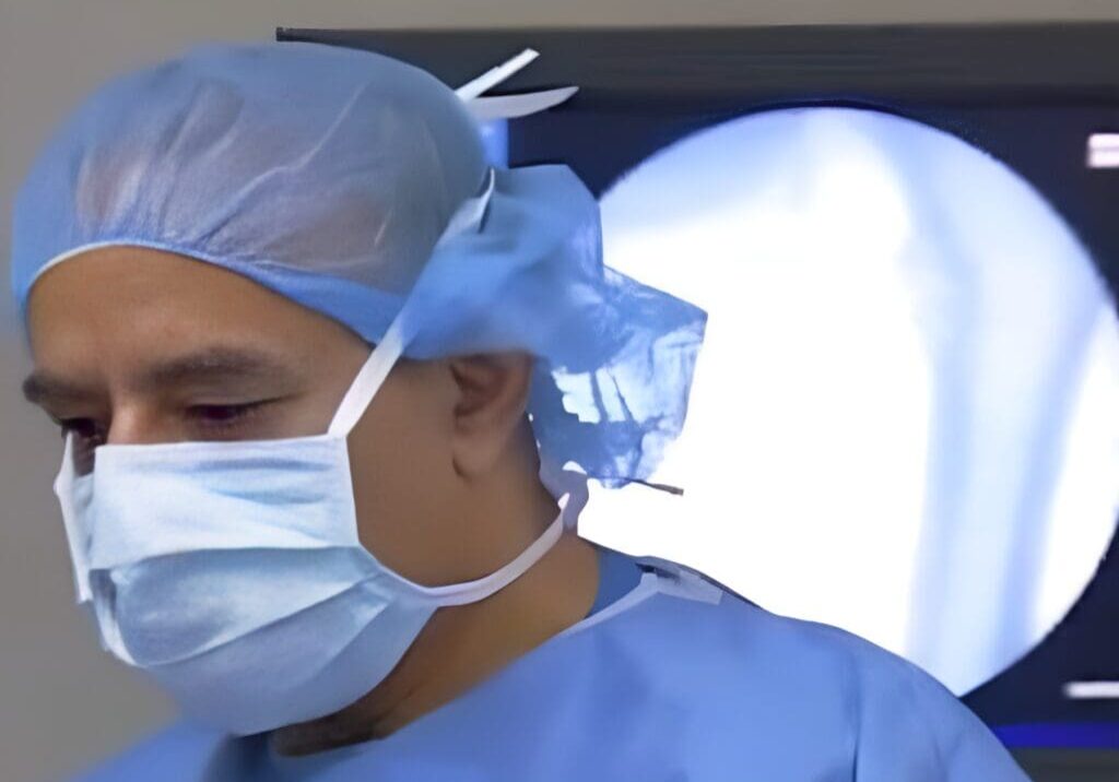 A surgeon wearing surgical masks and blue scrubs.