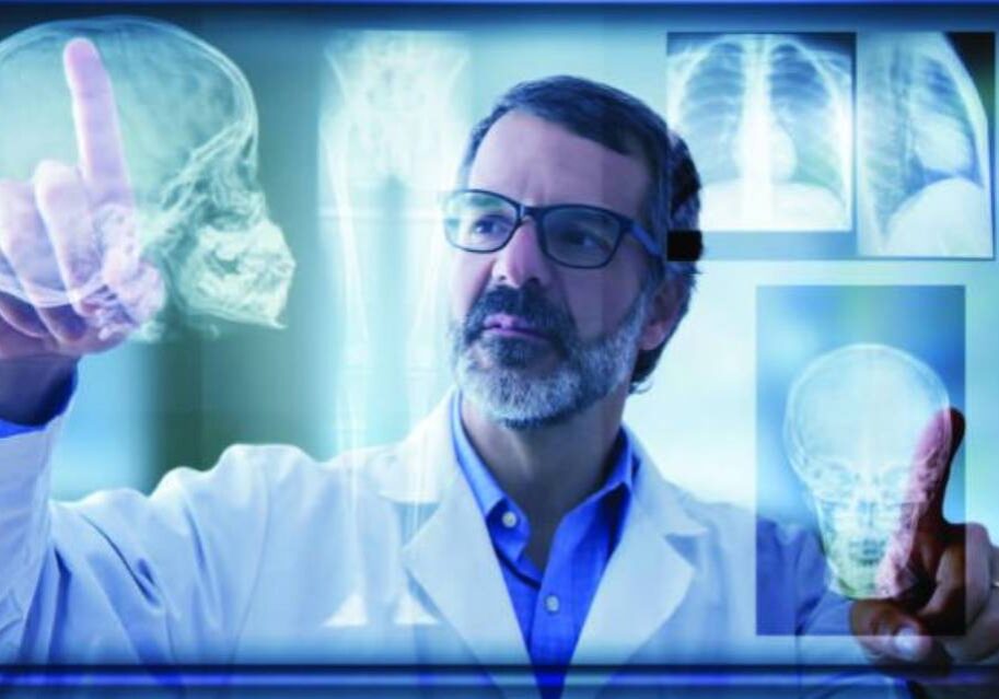 A man in glasses and lab coat looking at an x-ray.