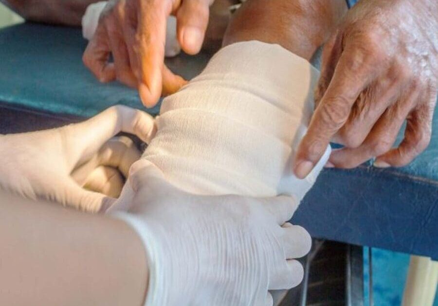 A person bandaging someone 's arm with gauze.