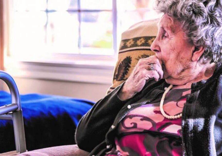 An older woman sitting on a chair talking on the phone.