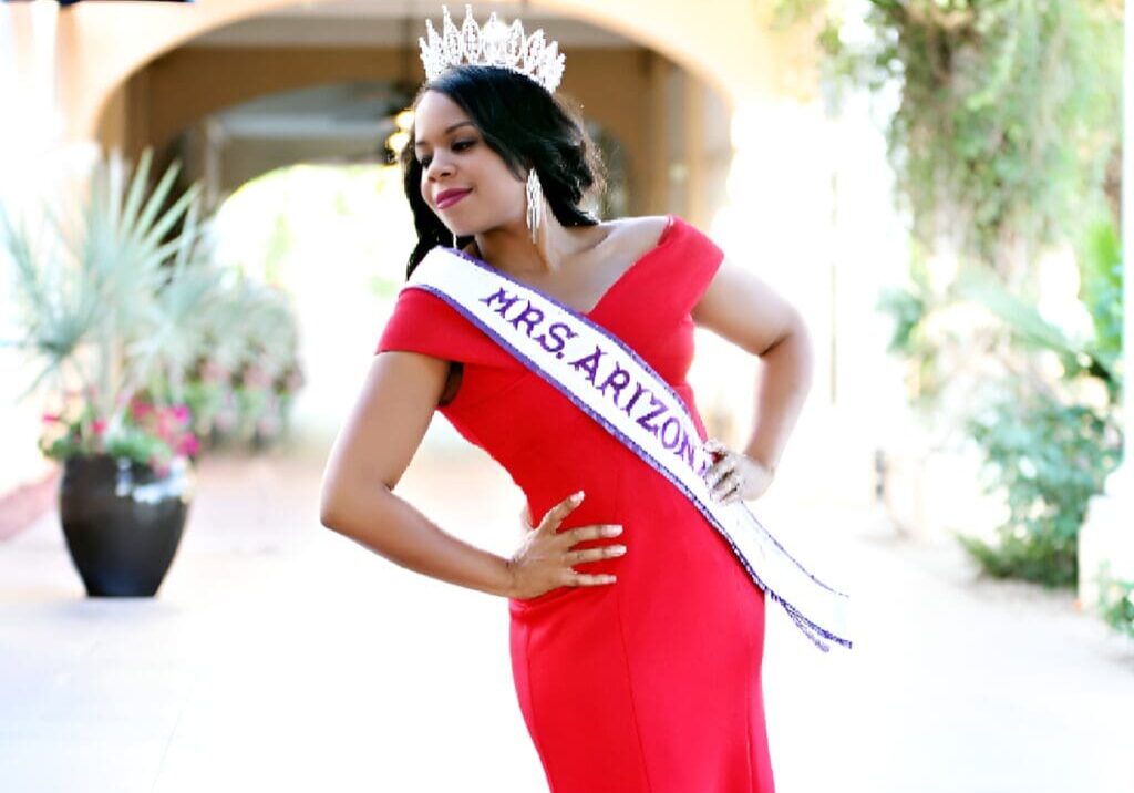 A woman in red dress and crown posing for the camera.
